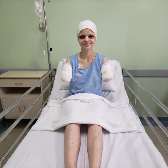 Sophia na cama do hospital, com os dois braços enfaixados